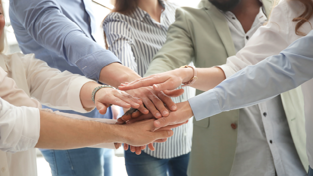 Coworkers throwing hands in center of circle to indicate teamwork