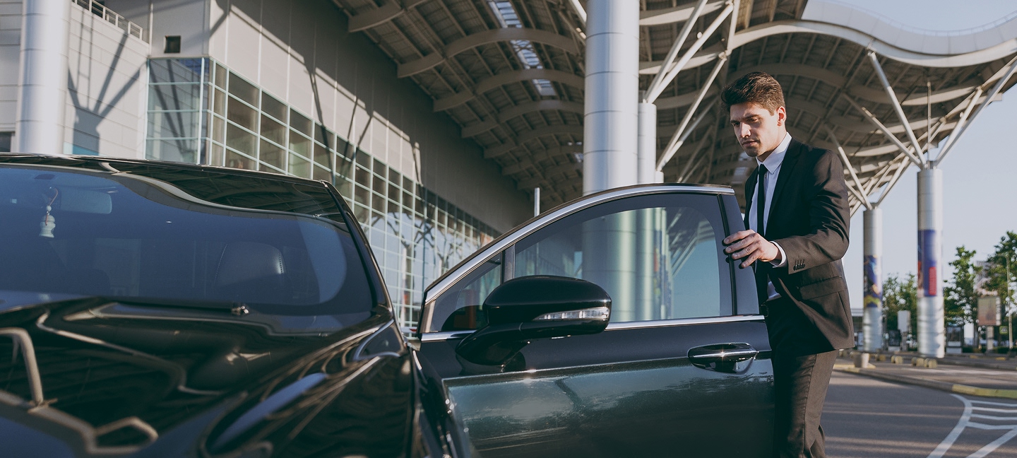 Man in a suit getting into a black car