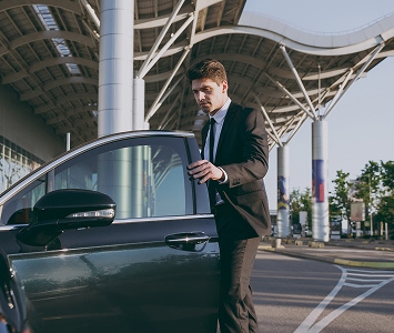 Man in a suit getting into a black car