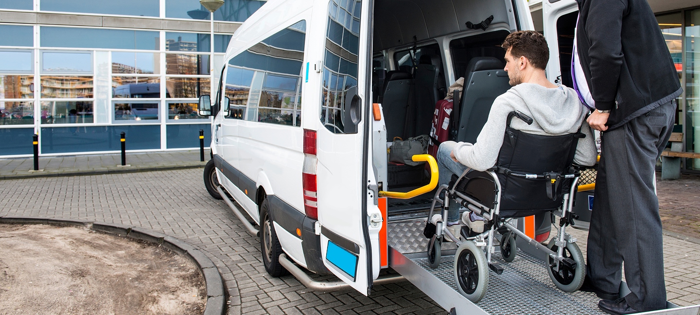 Man in a wheelchair being helped into the back of an accessible van
