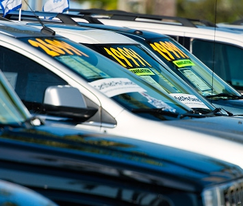 Cars in a used car lot with the prices on the window