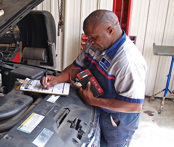 Mechanic working on a car with a clipboard