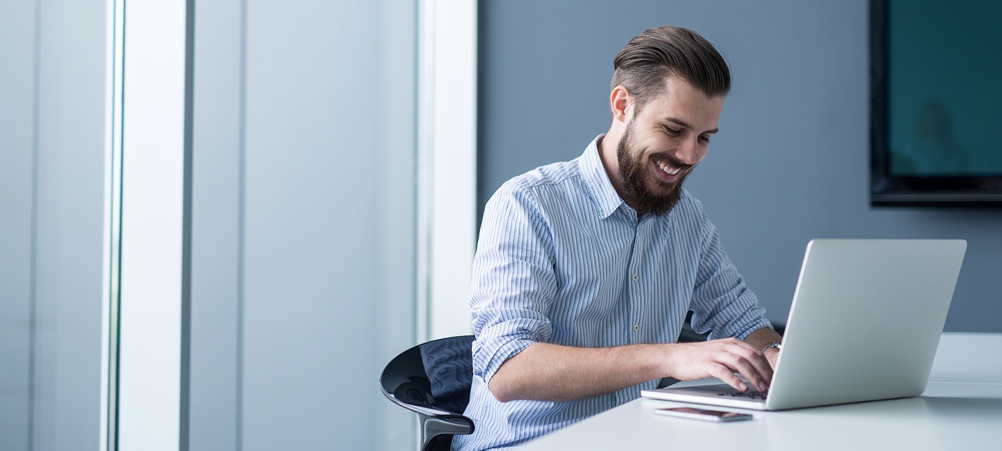 Happy man working on a silver laptop