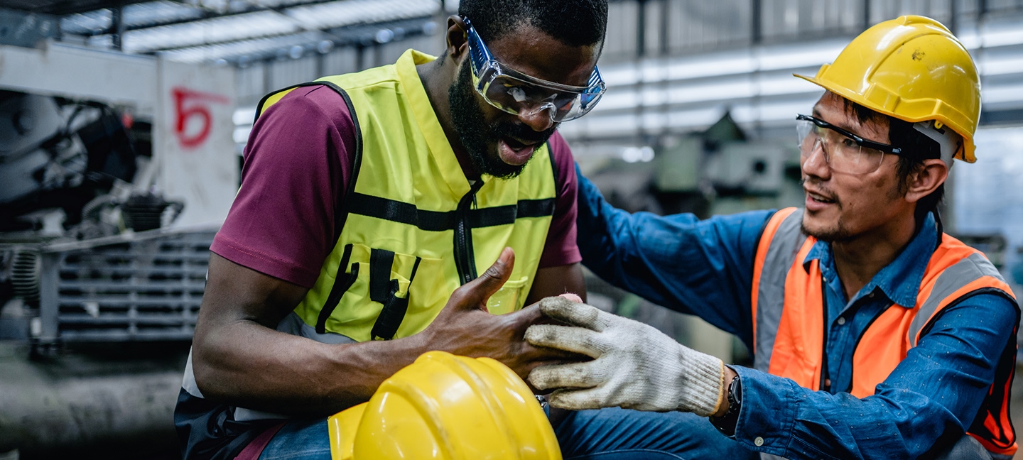 Worker consoling another worker holding their hand and looking in pain