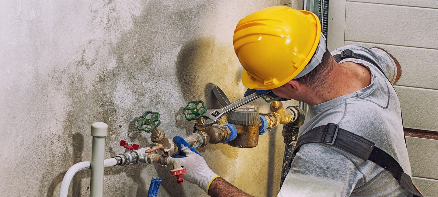 Contractor fixing piping on a concrete wall